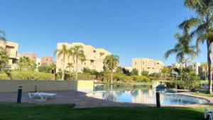 a resort with a pool and palm trees and buildings at La Perle de Marrakech in Marrakesh