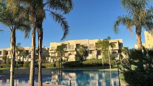 a building with palm trees in front of a pool at La Perle de Marrakech in Marrakesh