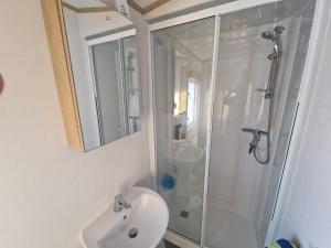 a white bathroom with a shower and a sink at Georgina Meadows in Skipsea +13 photos