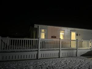 a white house with a white fence at night at Georgina Meadows in Skipsea