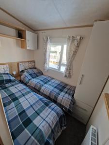 two beds in a small room with a window at Georgina Meadows in Skipsea