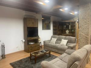 a living room with a couch and a tv at Douro Elegance Suites in Torre de Moncorvo