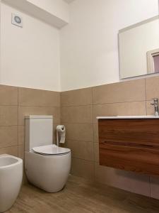 ein Badezimmer mit weißer Toilette und Waschbecken in der Unterkunft Capizzi Rooms in Bronte