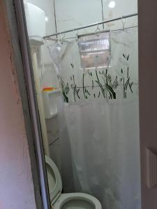 a bathroom with a toilet and a shower curtain with plants at Casa Singela in Miguel Pereira +4 photos