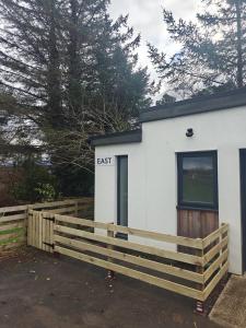 a white building with a fence in front of it at Viewpoint Pods in Dunollie