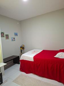 a bedroom with a red bed and a white wall at Comfort right on the sand! in Paracuru