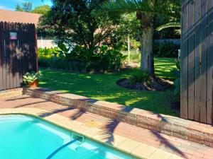a swimming pool in a yard with a tree at Ceelee's Place in Bloemfontein