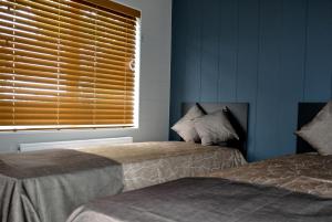 a bedroom with two beds and a window with blinds at Riverside Holiday Park in Amberley