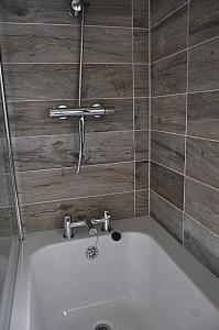 a bath tub in a bathroom with wooden tiles at Riverside Holiday Park in Amberley