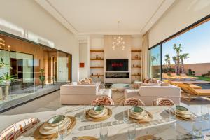a living room with a table and chairs and a fireplace at Villa Atlas - Luxe - 4 Suites Modernes - Fitness - Piscine Chauffée - Terrain de Padel - Vue Montagne in Marrakesh +68 photos