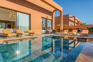 a swimming pool with chairs and a house at Villa Atlas - Luxe - 4 Suites Modernes - Fitness - Piscine Chauffée - Terrain de Padel - Vue Montagne in Marrakesh