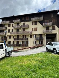 a large building with cars parked in front of it at La Cabine Noire - Foppolo in Foppolo