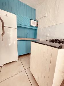 a kitchen with blue cabinets and a white refrigerator at Vista Mar Praia da Lagoinha - Residencial Pé na Areia in Bombinhas