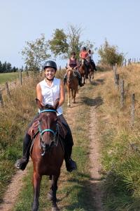 a group of people riding horses down a dirt road at Ferme Équestre Equi'Cantal in Montboudif +9 photos