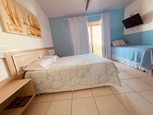 a bedroom with a bed and a television in it at Vista Mar Praia da Lagoinha - Residencial Pé na Areia in Bombinhas