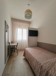 ein Schlafzimmer mit Bett, Schreibtisch und Fenster in der Unterkunft Hotel Marta in Forlì