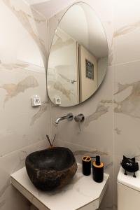 a bathroom with a stone sink and a mirror at DM Seaside House in Perissa