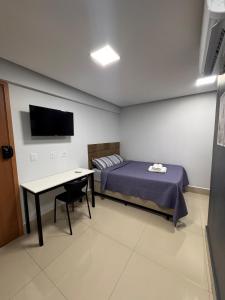 a bedroom with a bed and a desk and a tv at Studio em Anápolis in Anápolis +15 photos
