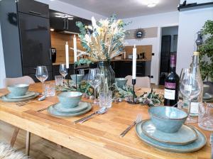 a wooden table with plates and wine glasses on it at Haus im Grünen l Hot Tub l aktivCARD inklusive in Regen