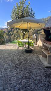 a table and chairs under an umbrella on a patio at Cantinho Verde T3 in Geres +14 photos