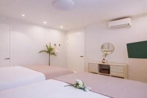 a white bedroom with two beds and a tv at Hongdae#Hongik Univ Station 9 min Walk#Airport Railroad Access#Free Parking#Free Netflix#Free WiFi#Luggage Storage#Washer and Dryer in Seoul