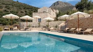 a pool with umbrellas and chairs and a house at Eleonas Limeni in Limeni