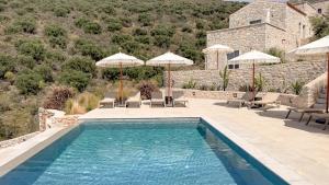a swimming pool with chairs and umbrellas next to a building at Eleonas Limeni in Limeni