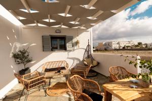 a patio with wicker chairs and a table and a table and a table at DM Seaside House in Perissa