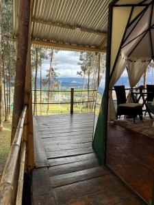 an open door to a wooden deck with a table at GLAMPING RESERVA CATEDRAL Zipaquira in Zipaquirá