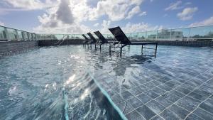 a group of chairs sitting in a pool of water at Flat Premium no Centro de Porto de Galinhas - Próximo as piscinas naturais in Porto De Galinhas