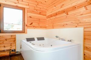 a white tub in a bathroom with a wooden wall at Ferienhaus Ustronie I Nr 1 in Ustronie Morskie +12 photos