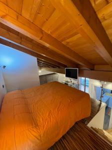 a bedroom with an orange bed and a television at Homely - Malpensa & Fiere Milano in Cardano al Campo