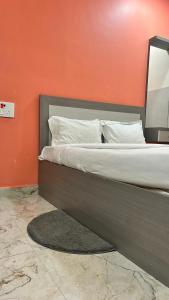 a bed in a room with an orange wall at Hotel Monsoon in Warangal