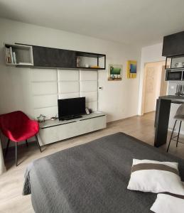 a bedroom with a bed and a red chair at Sunset Studio Apartment in Poprad