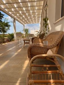 a porch with wicker chairs and a pergola at Arneo Rooms in Torre Lapillo +28 photos