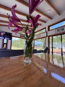 a vase with purple flowers sitting on a table at Casa en el bosque-tinaja in Puerto Octay