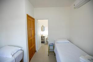 two beds in a room with a door and a table at QUINTAL DO SON CHALÉS in Ubatuba