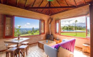a living room with a table and chairs and windows at Magnificat Cottage in Cunha