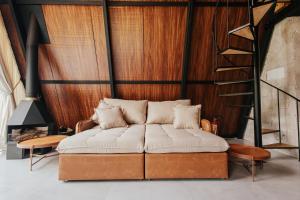 a couch in a room with a wooden wall at Chalé Rio das Pedras - Chalé 03 in Chapecó