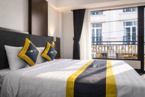 a bedroom with a large bed with yellow and blue pillows at Moonlight Boutique Hotel in Hue