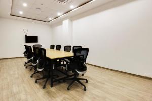 a conference room with a wooden table and black chairs at Super townhouse moosapet Rcc Prime in Hyderabad