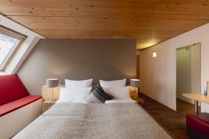 a bedroom with a large bed and a red couch at Skihotel Galzig B&B in Sankt Anton am Arlberg