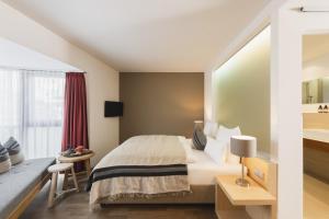 a hotel room with a large bed and a bathroom at Skihotel Galzig B&B in Sankt Anton am Arlberg