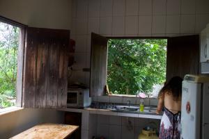 a woman standing in a kitchen looking out a window at Casa Kahlo in Lençóis