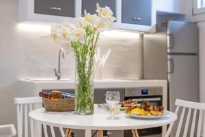 a table with a vase of flowers and a plate of food at Little Yard Studios & Apartments #4 in Naxos Chora