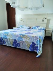 a bedroom with a bed with a blue comforter at Varanda das Palmeiras in Cairu +6 photos