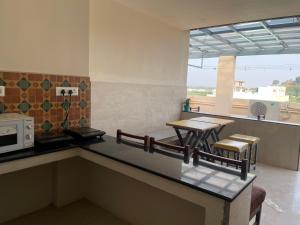 a kitchen with a counter and a table and chairs at Raghav Residency in Vellore