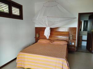 a bedroom with a bed with an umbrella above it at Varanda das Palmeiras in Cairu