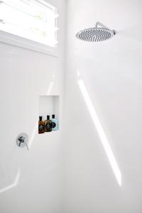 eine weiße Küche mit Deckenleuchte und Kühlschrank in der Unterkunft Bask & Stow I Luxe Guesthouse in Byron Bay + 22 Fotos
