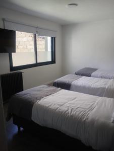 two beds in a room with a window at Hotel Manquehue in Esquel